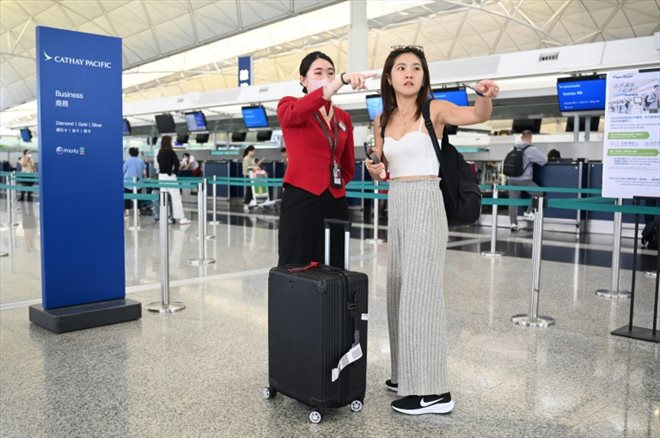 A l'aéroport de Hong Kong, le 4 septembre 2024, une hôtesse de Cathay Pacific renseigne les passagers