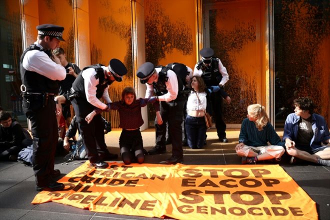 Des policiers délogent des militants du groupe écologiste Just Stop Oil qui ont aspergé de peinture le siège de TotalEnergies, pour dénoncer un mégaprojet pétrolier en Ouganda, le 27 juin 2023 à Londres