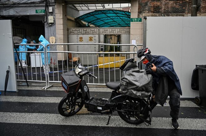 A delivery man on a scooter brings an order to the entrance of a confined area of ​​Shanghai after the appearance of new cases of Covid-19, on March 17, 2022 in China.