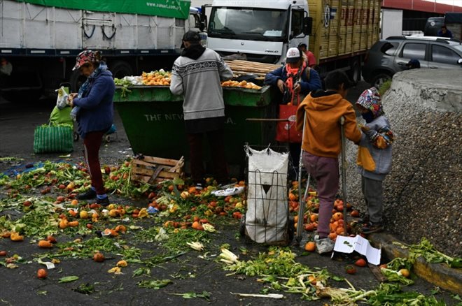 Limpia Benitez (g) et Gladys Meza (d) récupèrent des fruits et des légumes en bon état dans une benne à ordure du Marché central de Buenos Aires, le 9 juin 2023 en Argentine