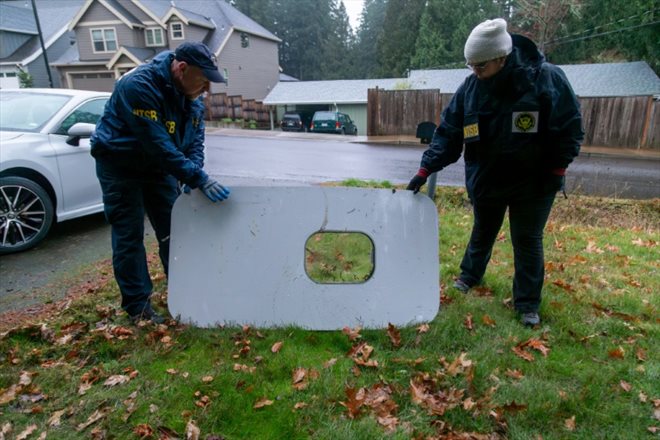 Photo released by the NTSB on January 8, 2024, shows officers inspecting a fallen door from an Alaska Airlines plane in Portland, Oregon