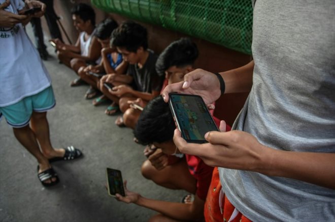 Des gamers jouent sur leurs smartphones au jeu vidéo NFT Axie Infinity, le 15 décembre 2021 à Malabon, dans la banlieue de Manille, aux Philippines