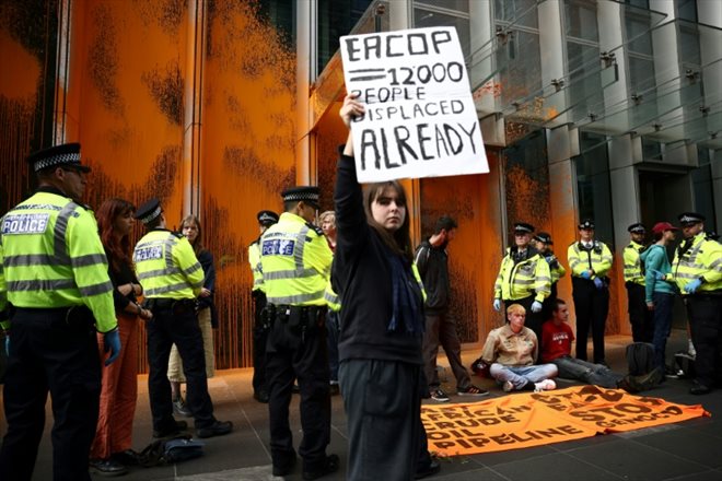 Des policiers entourent des militants du groupe écologiste Just Stop Oil qui ont aspergé de peinture le siège de TotalEnergies, pour dénoncer un mégaprojet pétrolier en Ouganda, le 27 juin 2023 à Londres