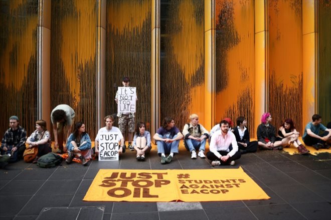 Des militants du groupe écologiste Just Stop Oil manifestent contre la construction de l'oléoduc de pétrole brut d'Afrique de l'Est (EACOP) après avoir jeté de la peinture orange sur le siège de TotalEnergies, le 27 juin 2023 à Londres