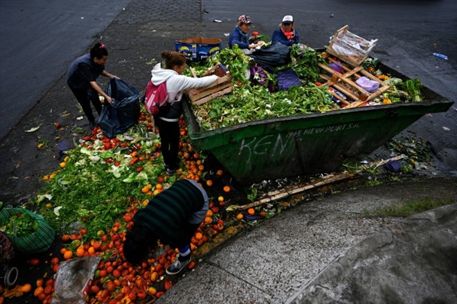 Limpia Benitez (d) et Gladys Meza (2e d) récupèrent des fruits et des légumes en bon état dans une benne à ordure du Marché central de Buenos Aires, le 9 juin 2023 en Argentine