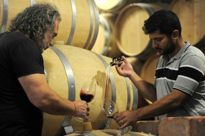 Marcelo Pelleriti (l), oenologist at the Monteviejo estate, and Jose Mounier, cellar master, taste wine drawn from a barrel, on March 14, 2023 in Flora Vista, Argentina